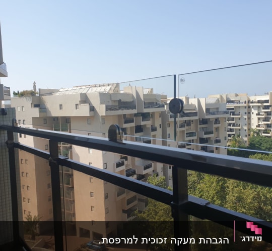 מעקה זכוכית עם נוף לבניינים ועצים